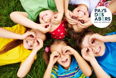 gros plan enfants allongés sur le dos dans l'herbe et faisant des formes de lunettes avec leurs mains