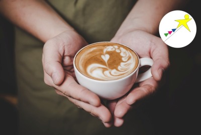 gros plan mains tenant une tasse de boisson chaude avec une forme de coeur dans la mousse