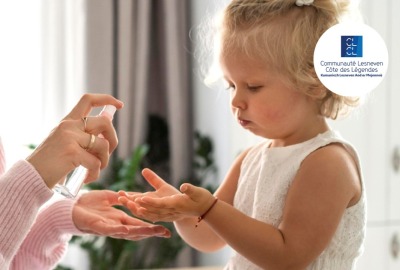 maman mettant du produit en spray sur les mains de sa petite fille