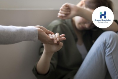 maint tendue vers une personne en train de pleurer, repliée dans un coin