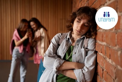 jeune fille triste en avant plan pendant que 2 jeunes filles avec téléphones se moquent d'elle en arrière plan