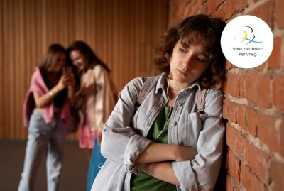 jeune fille triste au premier plan tandis que deux jeunes filles avec téléphone se moquent d'elle en arrière plan