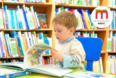 jeune garçon lisant un album dans une bibiliothèque