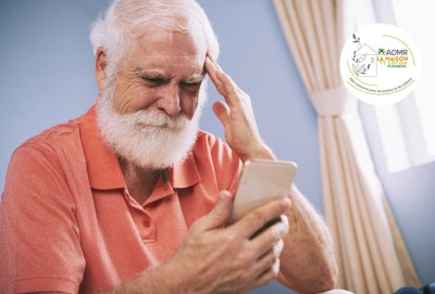 senior se touchant le front en regardant son téléphone, comme s'il avait oublié quelque chose