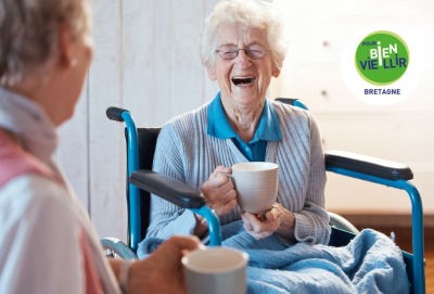 femme âgée riant aux éclats alors qu'elle prend le thé avec une autre personne, de dos