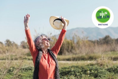 femme senior levant les bras en souriant à l'extérieur au soleil