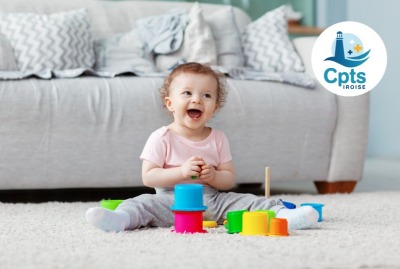 bébé jouant en souriant sur un tapis avec des jeux colorés